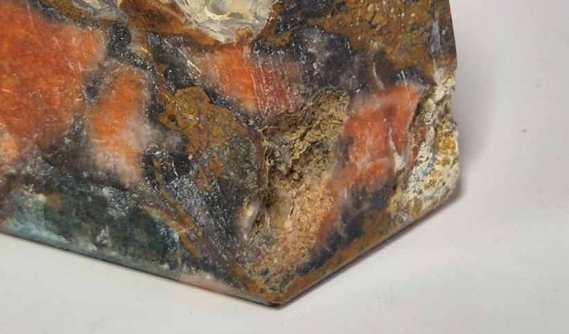 Pedra Natural Jaspe Policromo lapidada com tonalidades naturais em vermelho, marrom, creme e detalhes azulados exclusivos.